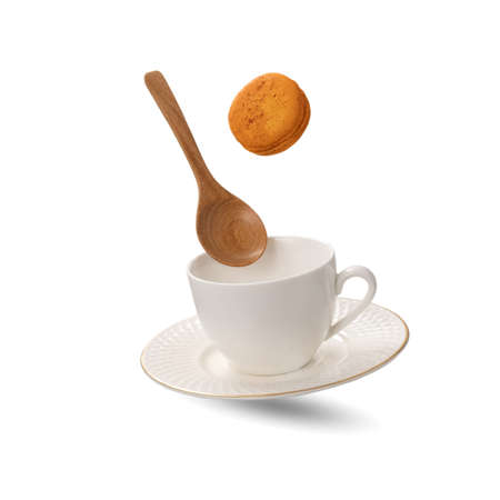 A white porcelain tea cup and a saucer with a wooden spoon levitating on white background.の写真素材
