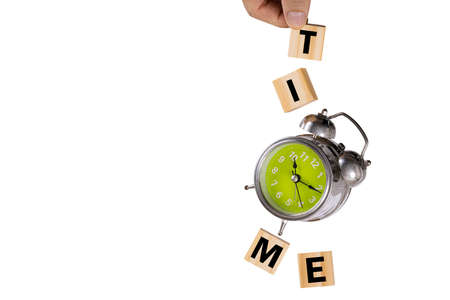 A hand catching a falling rusty old alarm clock and four wooden cubes spelling 'time'. Levitation photography, 'time' concept.の写真素材