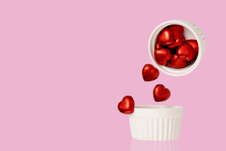 Heart shaped chocolate candies falling from a ceramic cup. Levitation food photography.の写真素材