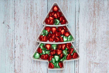Heart shape chocolate candies on pine shape plate, Christmas snack on pale blue wooden background.の写真素材