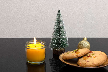 Christmas table decorations with scented candle and a plate of orange peel biscuits.