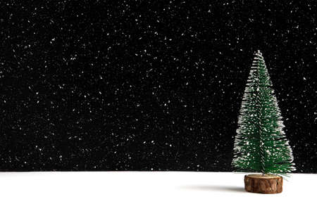 A miniature Christmas tree with snow flakes on black and white background.の写真素材