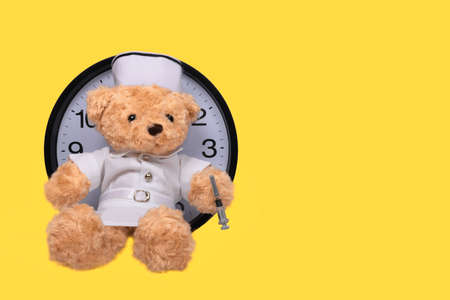 A toy bear holding a vaccine syringe.  Third vaccination booster dose for covid 19 prevention concept.の写真素材