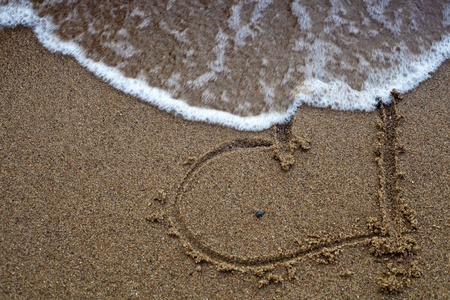 Disappearing heart drawn on the beach sand.の写真素材