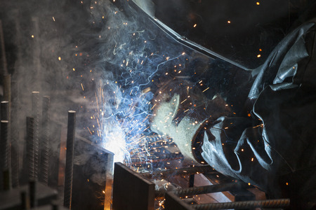 Industrial worker welding steel in the dark