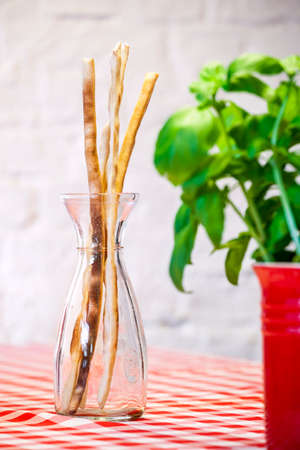 Italian crusty Grissini appetizer with fresh basil in a foregroundの写真素材