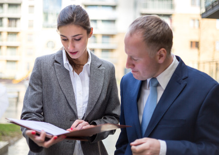 Two business people standing and discussingin front of the officeの写真素材