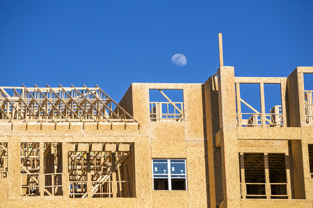 Big multifamily housing under construction against blue sky