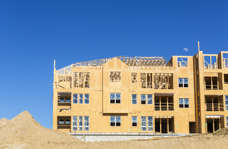 Big multifamily housing under construction against blue sky Big multifamily housing under construction against blue sky
