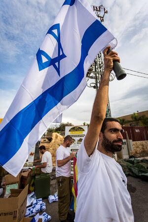 Mount Carmel, Israel - October 28, 2015: Israeli soldier with national flag. Group of them was installing Israeli flag before bicycle race.のeditorial素材