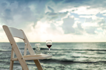 White chair with wineglass on a beach left after wedding banquetの写真素材