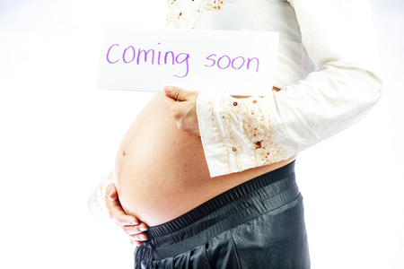 Pregnant woman holding sign regarding her baby: coming soonの写真素材