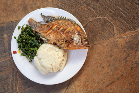Traditional East African food - ugali, fish and greens in Kenyaの写真素材