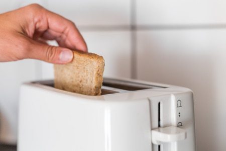 Putting a slice of bread to the white toasterの写真素材