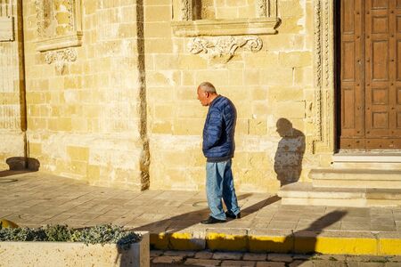 Gallipoli, Italy - March 3, 2017: Elderly man walking through sunny street of Italyのeditorial素材