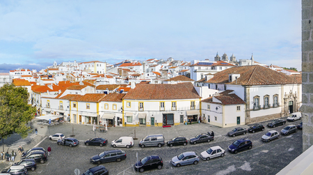 Panoramic view of the roofs of the historic old town taken from a nearby building, with a parking lot and cafes in the first plan, Evora, Alentejo, Portugalのeditorial素材