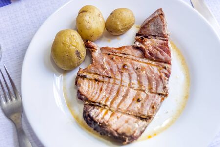 Juicy tuna steak with potatoes served on white plateの写真素材