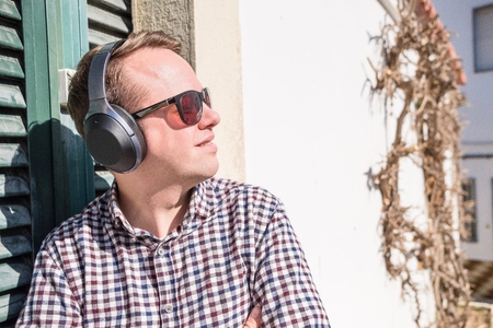 Young man enjoying the music from fancy modern headphones outdoorの写真素材