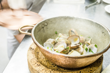 Portion of clams fried with garlic and coriander in a copper pot in the restaurantの写真素材