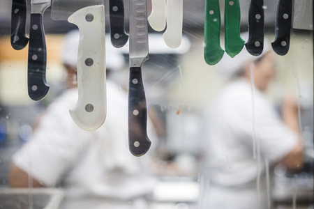 Unfocused restaurant's kitchen workers through window with knifes