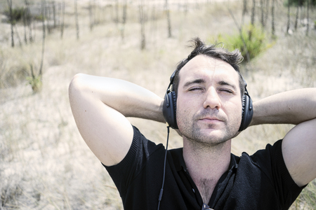 Young attractive man wearing black enjoying music on his headphonesの写真素材