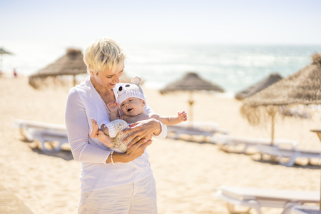Happy mom playing with her cheerful son on the beachの写真素材