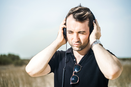 Young attractive man wearing black enjoying music on his headphonesの写真素材