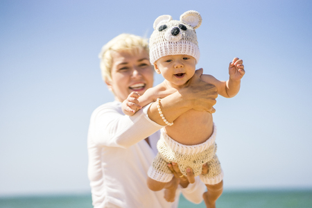 Happy mom playing with her cheerful son on the beachの写真素材