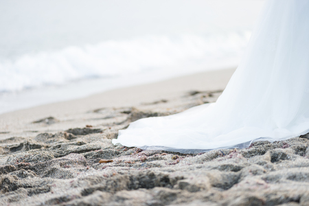 Lower part of long wedding dress on the beachの写真素材