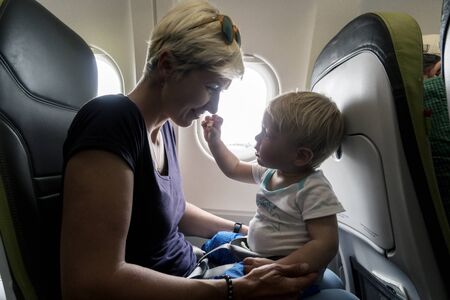 Mother with small baby son playing in the airplane during the flightの写真素材