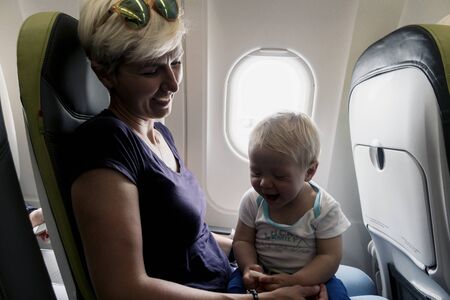 Mother with small baby son playing in the airplane during the flightの写真素材