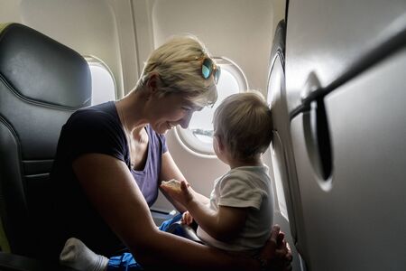 Mother with small baby son playing in the airplane during the flightの写真素材
