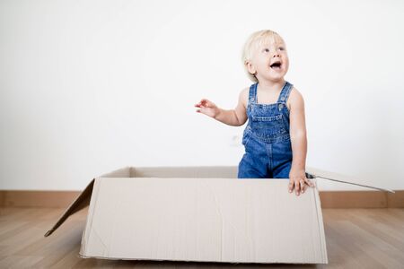Cute blond toddler jumping out of the boxの写真素材