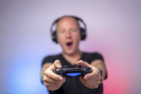 Gamer with headphones and gamepad having a lot of fun. Gamepad in