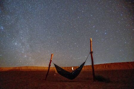 Lonely green hammock next to dunes on Sahara desert with amazing starry sky above, Moroccoの写真素材