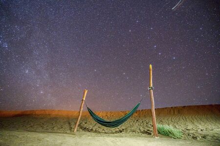 Lonely green hammock next to dunes on Sahara desert with amazing starry sky above, Moroccoの写真素材