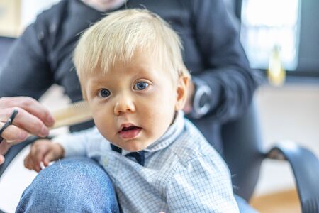Blond baby boy with blue eyes at the hairdresser salonの写真素材