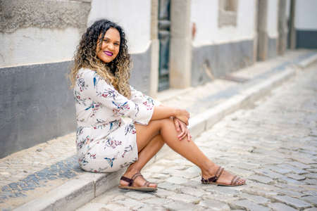 Beautiful woman sitting on the pavement of cute portuguese streetの写真素材