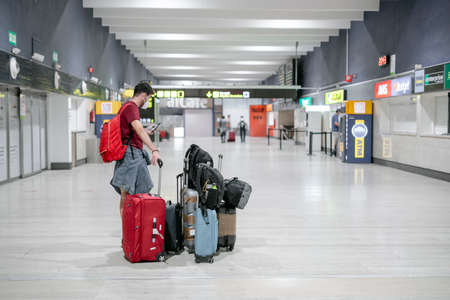 Seville, Spain - July 25, 2020: Man wearing mask waiting at the airport with many bags.のeditorial素材