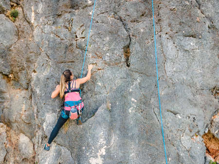 A woman in harness climbing a steep rock in Portugalの写真素材