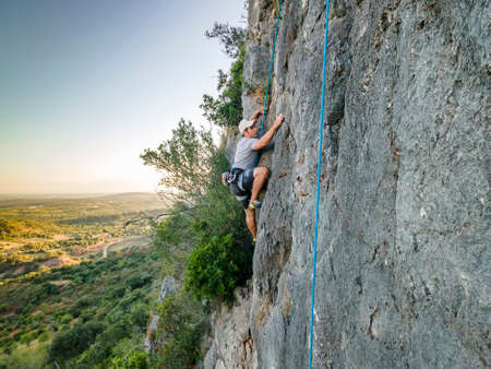 Man climbing a steep, plain rock in Portugalの写真素材