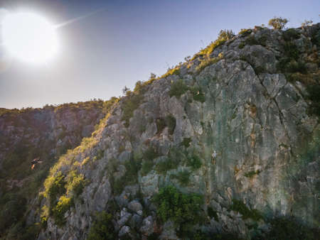 Man climbing a steep, plain rock in Portugalの写真素材