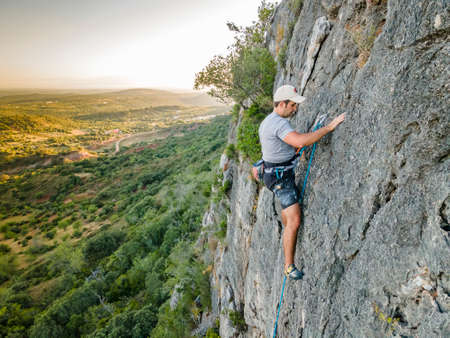 Man climbing a steep, plain rock in Portugalの写真素材