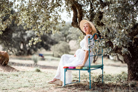 Elegant pregnant woman on colorful bench by cork treeの写真素材