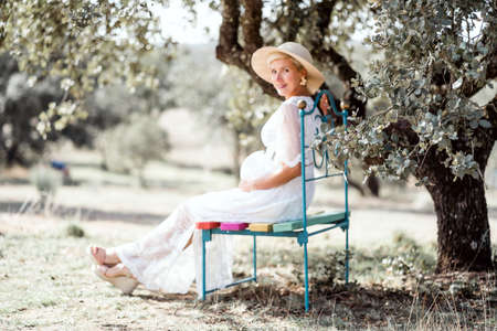 Elegant pregnant woman on colorful bench by cork treeの写真素材