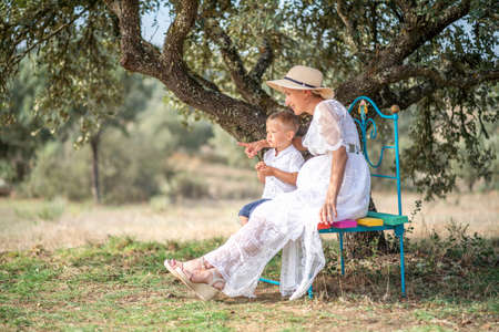 Pregnant woman spending time with her little son in the natureの写真素材