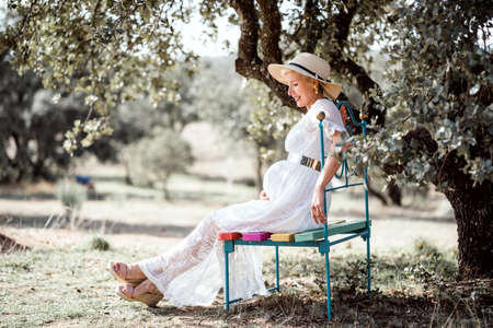 Elegant pregnant woman on colorful bench by cork treeの写真素材