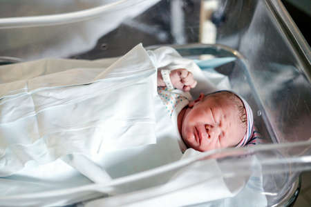Newborn baby boy in a small hospital bed two hours after birthの写真素材