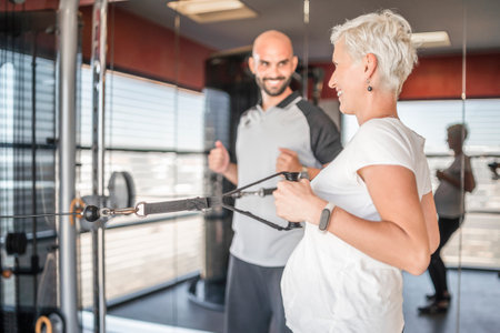 Pregnant woman exercising in an indoor gym with a personal trainerの写真素材