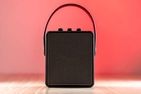 Black modern bluetooth loudspeaker on a reddish backgroundの写真素材